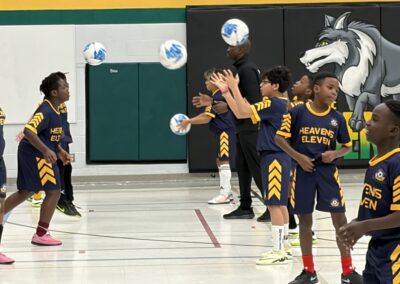 Young basketball players in blue and yellow uniforms practicing shots on an indoor court.