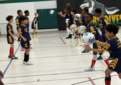 Children playing indoor flag football, lined up for a drill.