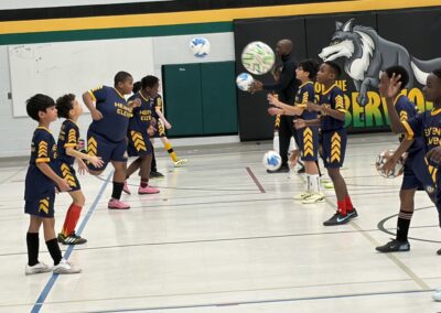 Children playing soccer indoors, focusing on ball control.