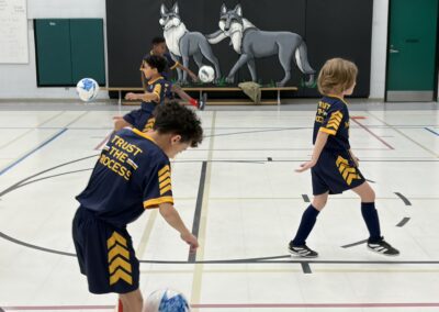 Children playing floor hockey in a gymnasium.
