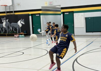 Young boys playing indoor basketball in a school gym.