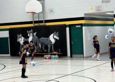Children playing basketball in a gym with wolf murals.