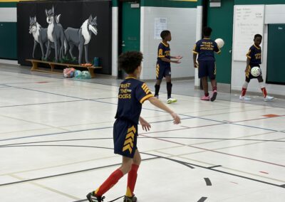 Young boys playing indoor soccer in a gymnasium.