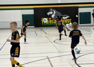 Kids playing indoor soccer in a gymnasium.