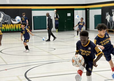 Kids playing indoor soccer in a gym.