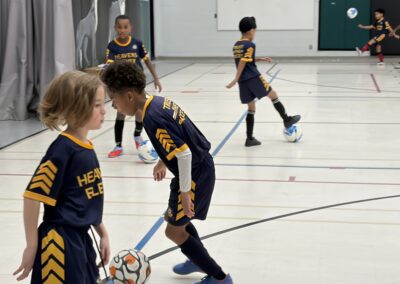 Children playing indoor soccer in a gymnasium.