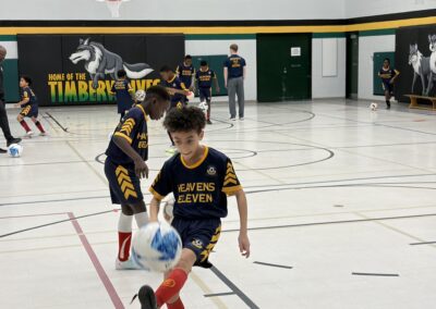 Young boys playing indoor soccer in a gymnasium.