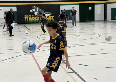 Young boy balancing a soccer ball on his foot indoors.