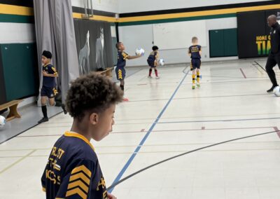 Young boys playing indoor soccer in a gymnasium.