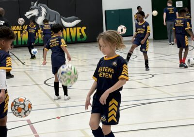 Young soccer players practicing ball control indoors.