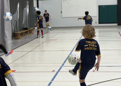 Children playing indoor soccer practice in a gym.