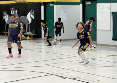 Children playing indoor soccer in a gymnasium.