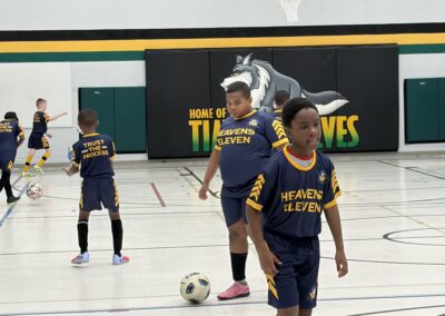 Youth soccer players in navy and yellow uniforms practicing indoors.