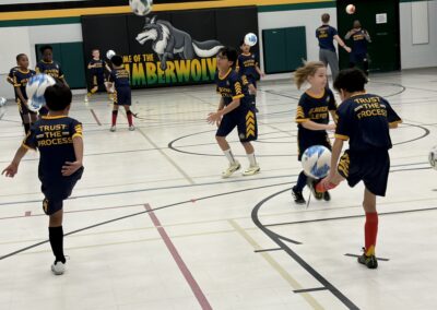 Kids playing indoor soccer in a gymnasium.