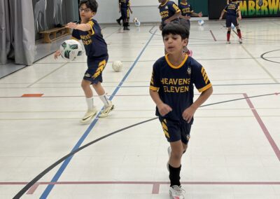 Kids playing indoor soccer practice in a gymnasium.