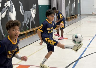 Boys playing indoor soccer, focusing on kicking the ball.