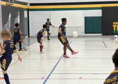 Kids playing indoor soccer in a gymnasium.