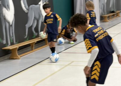 Kids playing indoor soccer, focused on ball control.