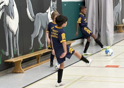 Young boys playing indoor soccer in a gymnasium.