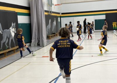 Children playing indoor hockey in a gymnasium.