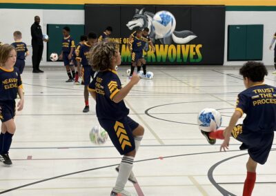 Youth soccer game with a player preparing to kick the ball indoors.