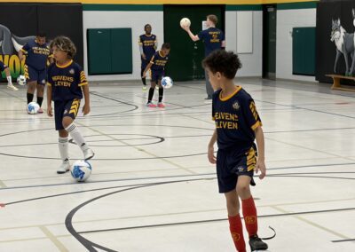 Kids playing indoor soccer in a gymnasium.