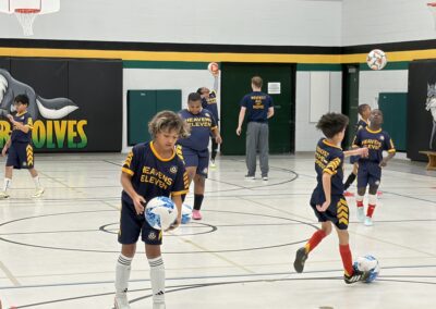 Youth basketball players in action during a game in a school gym.