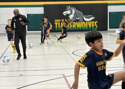 Kids playing indoor basketball in a gymnasium with a timberwolves banner.
