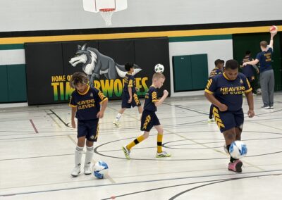 Young basketball players practicing dribbling drills in a school gym.