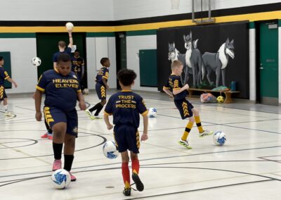 Children playing soccer indoors in a gymnasium.