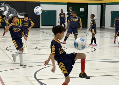Young boys playing indoor soccer in a gymnasium.