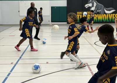 Children playing indoor soccer in a gymnasium.