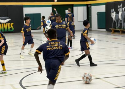 Youth soccer players in blue and yellow uniforms playing indoors.