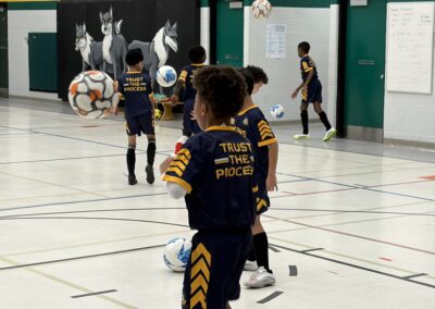 Kids playing indoor soccer in a gymnasium.