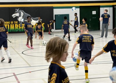 Children playing indoor soccer in a gymnasium.