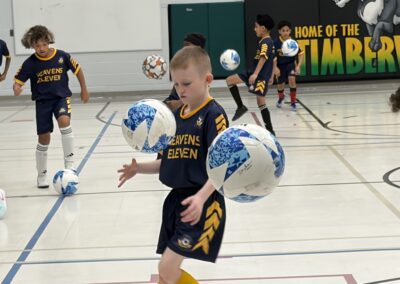 Young boy practicing soccer skills indoors with large soccer balls.