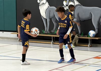 Two kids in basketball uniforms preparing to play indoors.