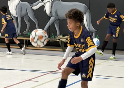 Young soccer goalie prepares to catch the ball indoors.