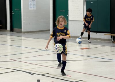 Young boy playing indoor soccer, controlling the ball mid-air.