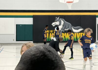 Youth basketball game with players and a mascot in a gym.