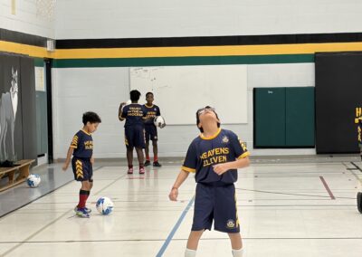 Kids playing basketball indoors, one looking up.