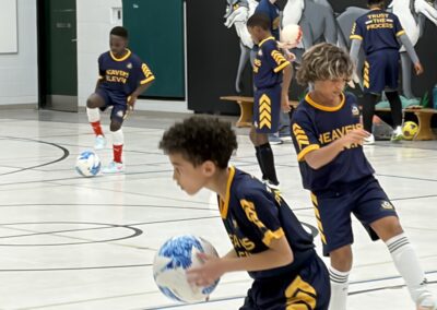 Kids playing indoor basketball, one holding a ball.