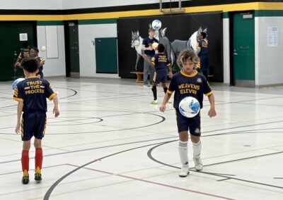 Children playing indoor soccer in a gymnasium.