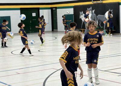 Kids in navy and yellow uniforms playing basketball indoors.