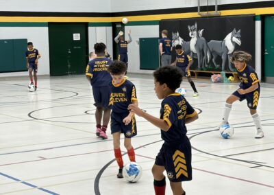 Young children playing basketball indoors wearing matching uniforms.