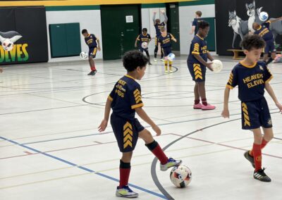 Young soccer players practicing indoors in a gymnasium.