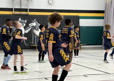 Children playing basketball indoors in matching uniforms.