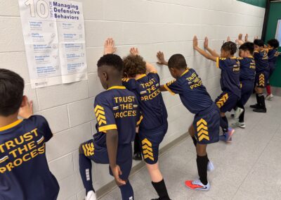 Young boys stretching before a basketball game in a school hallway.