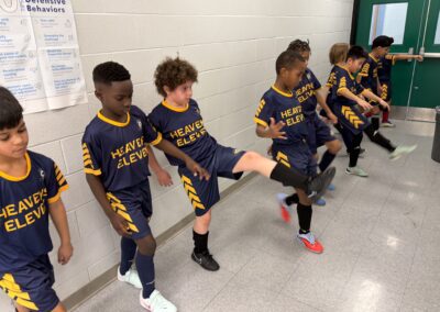 A group of young athletes stretching indoors in matching uniforms.