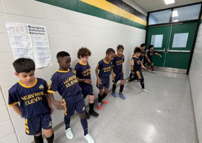 Young kids lined up indoors in matching sports uniforms.